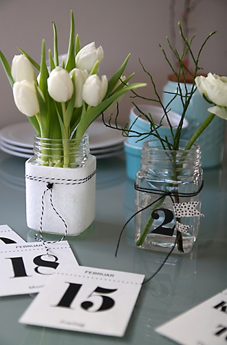 Tulpen im Glas mit Filz ummantelt und Kalenderblätter auf Tisch